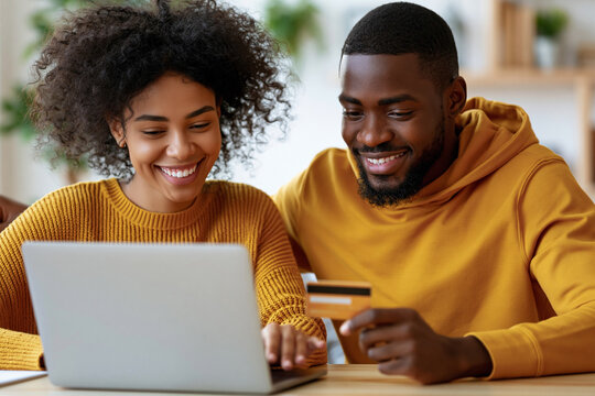 Affectionate couple shares a joyful moment online. They smile while shopping together on a laptop. One holds a credit card, suggesting a purchase. Warm tones and cozy setting enhance the mood