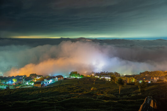 Breathtaking night view of Shizhuo in Alishan, Taiwan, featuring rolling tea plantations, glowing village houses, and a stunning sea of clouds under the night sky.