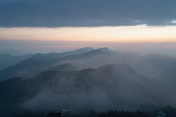Fototapeta premium Breathtaking night and sunrise view of rolling fog, distant mountain peaks, and tea plantations in Shizhuo, Alishan, Taiwan.