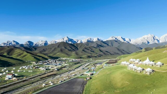Aerial time-lapse of Maya Snow Mountain with Grassland and Tibetan Tent Camps at Morning, Gansu province, China.