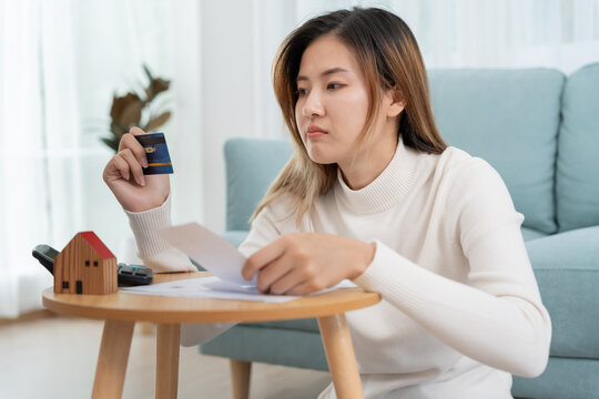 Debt house, Stressed and headache asian woman with large bills or invoices no money to pay, shortage, Financial problems, mortgage, loan, bankruptcy, bankrupt, poor, empty wallet, overdue