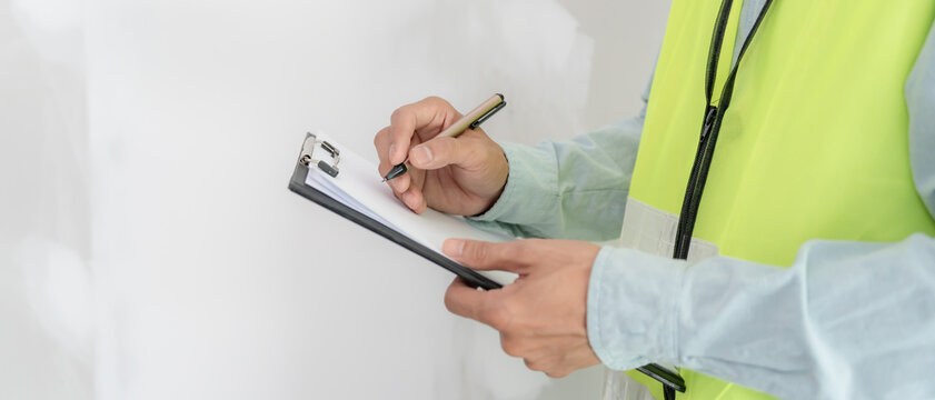 inspector or engineer is inspecting construction and quality assurance new house using a checklist. Engineers or architects or contactor work to build the house before handing it over to the homeowner