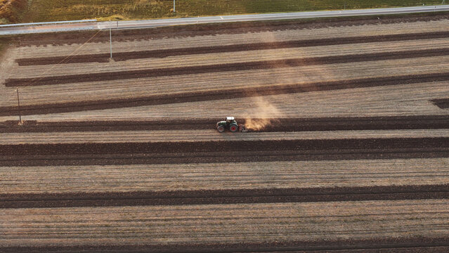 Tractor cultivating extensive agricultural fields, turning rich soil in the Po Valley, Emilia Romagna, Italy, illustrating modern farming techniques and land preparation for future crops
