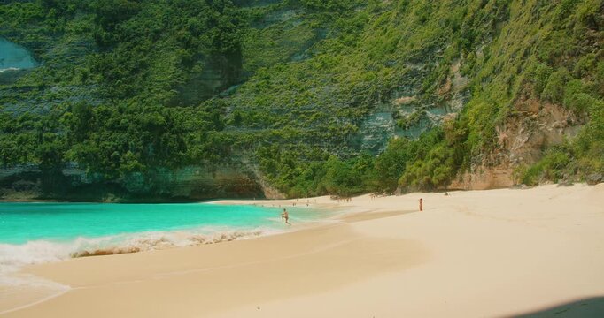 Turquoise ocean waves and green cliffs at sandy Kelingking Beach Bali Nusa Penida