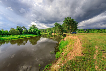 Fototapeta premium River reflects stormy sky under thick cloud cover