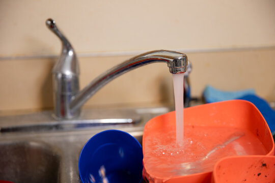 Chrome faucet drips water into an orange dish