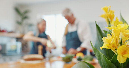 Fototapeta premium Old couple, cooking and kitchen at house with flowers, blossom and romance for breakfast. Senior people, helping and floral bouquet in home with meal prep, blooming season and household decoration