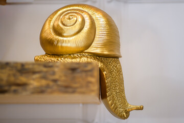 Golden snail sculpture on a wooden surface shelf modern artistic design and craftsmanship - horizontal © Natsky