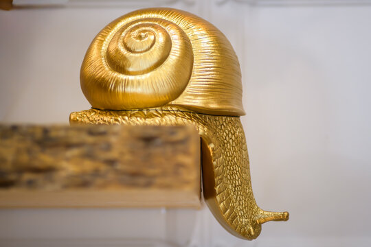 Golden snail sculpture on a wooden surface shelf modern artistic design and craftsmanship - horizontal