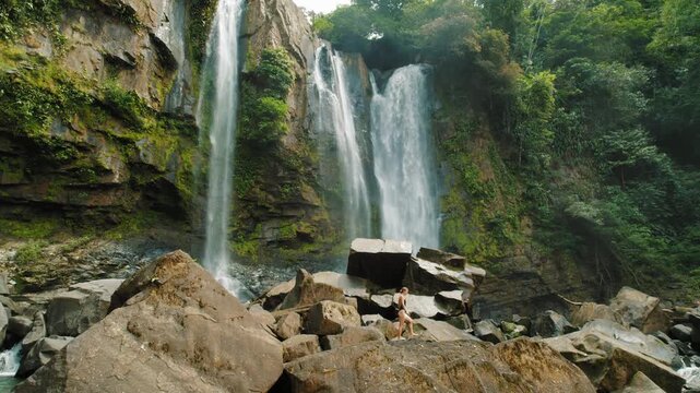 Woman exploring rocks near the base of Nauyaca Waterfalls in Costa Rica