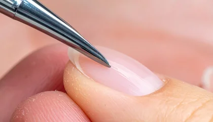 Meticulous nail care with a specialized tool gently pushing cuticles on a healthy natural fingernail. Professional manicure showing precise grooming and hygiene © avivmuzi