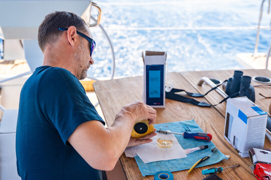 Man repairing yacht equipment with hand tools during a sailing trip on the Adriatic Sea. Concept of boat maintenance, DIY repair, seamanship, technical skills and self-sufficient sailing.