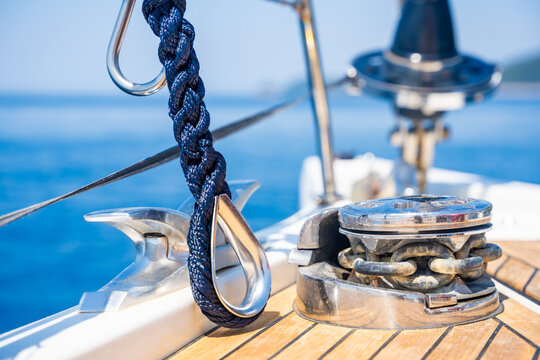 Mooring rope secured to a stainless steel cleat on the deck of a modern sailing yacht. Safe docking equipment and seamanship concept.