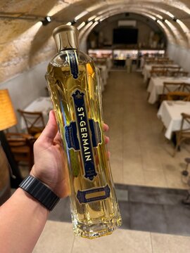 Palma, spain, august 2, 2026, hand holding st germain elderflower liqueur bottle in a bar, preparing for a refreshing drink