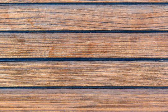 Close up of teak wooden decking on a sailing yacht creating a clean nautical texture and seamless background. Concept of marine design, luxury boating, craftsmanship and premium natural materials.
