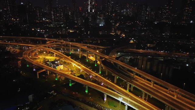 Drone hyperlapse aerial shot of Atal Setu in Mumbai at night, showcasing the dynamic cityscape illuminated with vibrant lights. The footage captures the fast-paced movement of traffic and clouds.