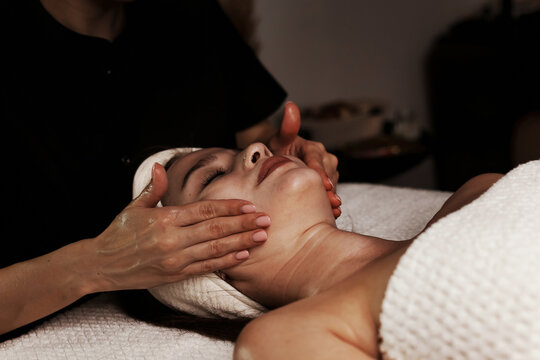 A skilled therapist gently performs a facial massage on a client, promoting relaxation and rejuvenation. The serene indoor setting enhances the soothing experience, highlighting self-care.