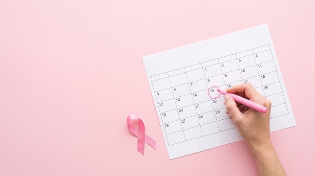 Hand Marking Date On Calendar With Pink Ribbon For Breast Cancer Awareness Month And Womens Health Checkup