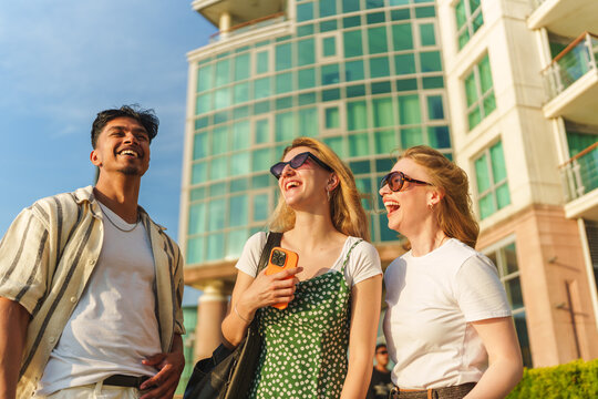 Three friends laughing together walking outdoors in a city setting
