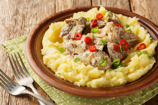 Homemade fried liver with onions and sour cream served with mashed potatoes close-up in a plate on the table. Horizontal
