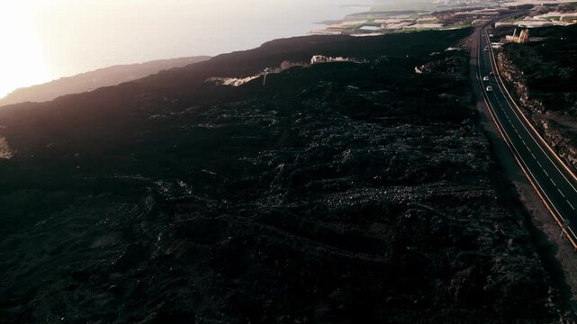 Warm morning light casts long shadows over a black lava field hiding the ruins of a buried village.