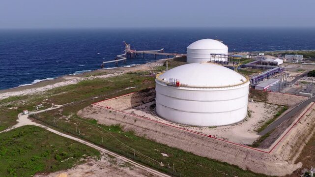 Wide aerial view of massive natural gas storage tanks and marine infrastructure beside the Caribbean Sea at AES Andres in Dominican Republic