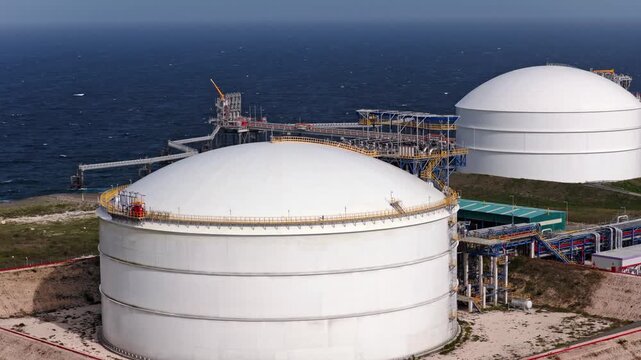 Drone view of massive natural gas storage tanks with pipelines and marine infrastructure along the Caribbean coast at AES Andres in Dominican Republic