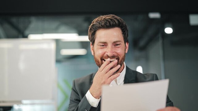 Professional reads important document, then celebrates with happiness and excitement. Overjoyed with news, triumphantly clenches fist.