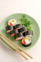 A green plate of fresh sushi maki rolls with chopsticks © Cavan