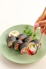 Hand with chopsticks holding a fresh sushi roll © Cavan