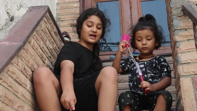Two Indian sisters playing with soap bubbles together at home.
Cute childhood moment showing siblings enjoying bubbles, fun, and playtime.