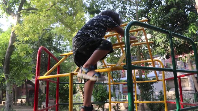 Indian girl climbing on playground equipment in a park.
Active outdoor play and fun childhood activity.