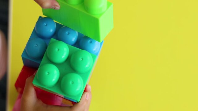 Watch as this small child's hands expertly assemble colorful plastic blocks, nurturing fine motor skills and sparking engineering thinking in early childhood development.