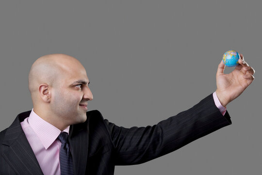 Bald businessman holding a tiny globe 