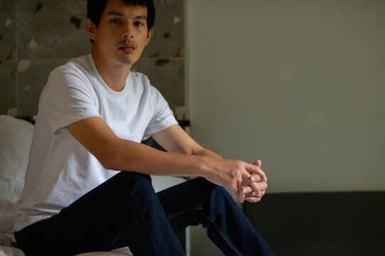 Young Man Sitting on Bed in Casual Attire with Natural Lighting