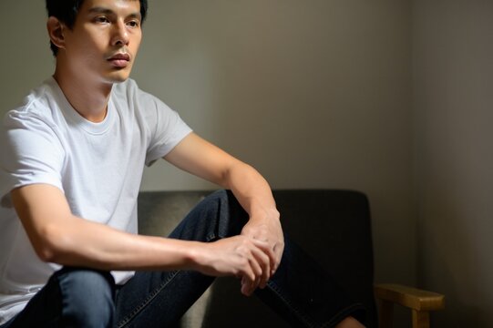 Thoughtful young man seated in calm indoor setting, natural light