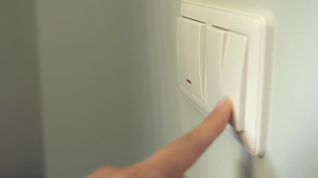 Turning electric lighting on and off in a room. Pressing a wall switch. A woman tests the lighting. She turns the light on and off.