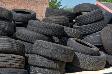 Pile of used car tires stacked outdoors on a sunny day.Large heap of old discarded black rubber tires for recycling. © Anna Kondratiuk