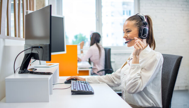 Smiling customer service agent wearing headset talking in office
