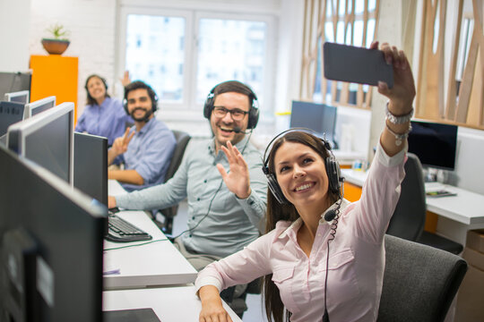Cheerful customer service team taking a selfie together in the office
