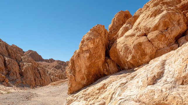 Rocky terrain features large, rugged boulders under clear blue sky, showcasing beauty of natural landscapes and geological formations