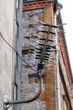Outdoor directional television antenna mounted on a residential building wall.The topics of traditional media versus modern internet streaming, modernization of old antenna systems, and the digitaliza