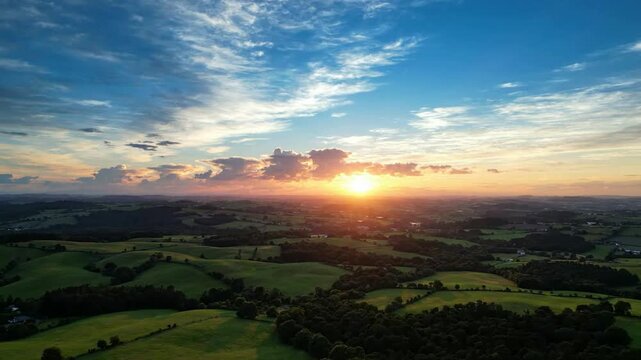 Aerial sunset over rolling green hills and countryside landscape at golden hour, cinematic nature background, for travel and, environmental projects
