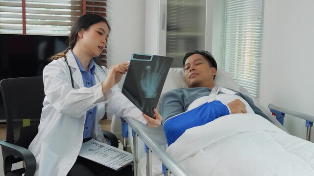Female doctor explaining hand x ray to patient in hospital bed