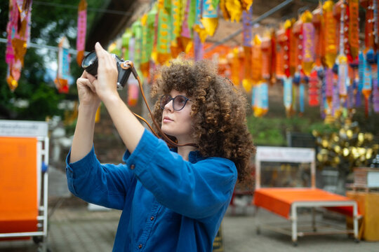 Caucasian Woman Tourist Taking Photos with Camera at Colorful Thai Temple Festival Decoration