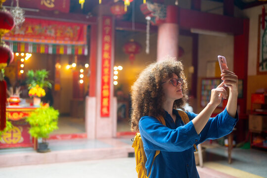 Caucasian Woman Travel Vlogger Taking Selfie at Colorful Chinese Temple with Red Lanterns and Decorations