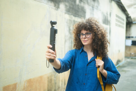 Caucasian Woman Travel Vlogger Recording Video with Gimbal Camera Outdoors on Urban Street