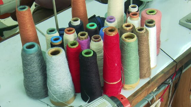 Colorful textile thread cones arranged in garment factory workshop representing sewing production and textile industry