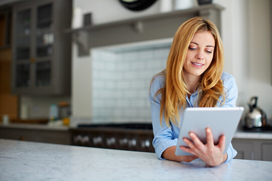 Woman, relax and reading at house with tablet, social media and browsing online for latest movies. Smile, person and rest in kitchen with digital app, internet search and streaming for film watchlist
