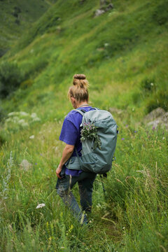 Woman with a backpack hikes through a green meadow